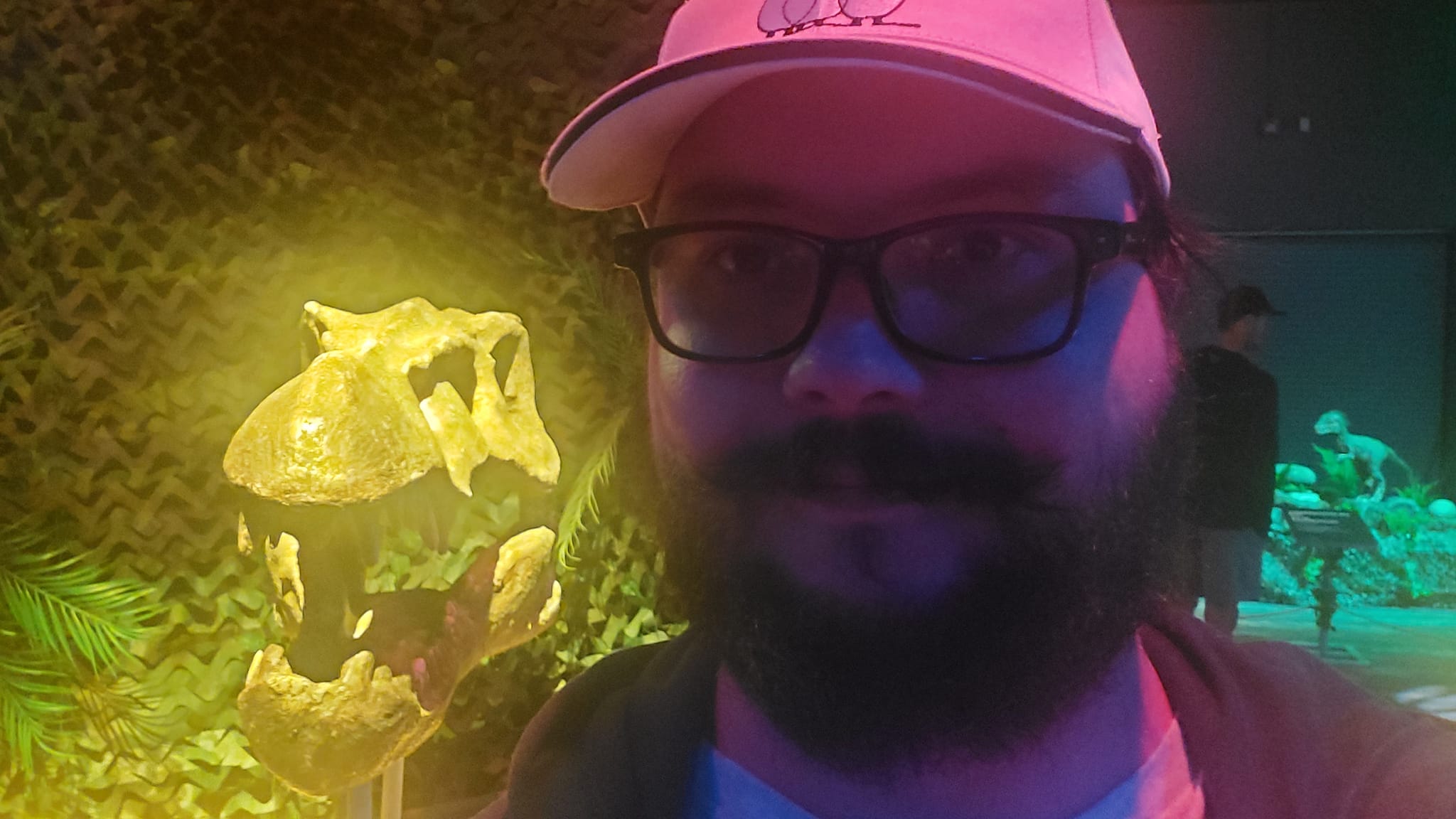 A man with a ball cap and bushy facial hair standing in front of a skull (which he forgot to identify)